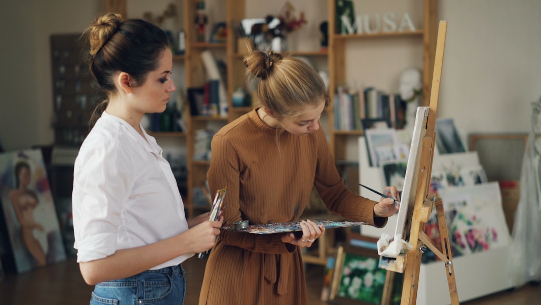 Two women are painting in an art studio.