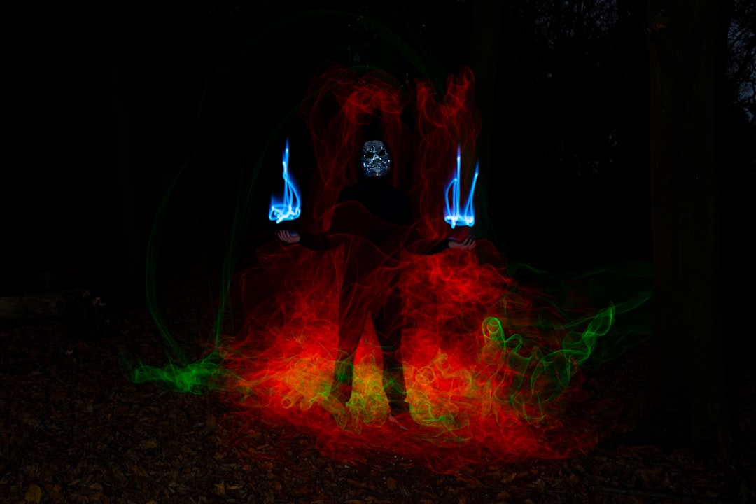 a man standing in a dark forest with red and green lights